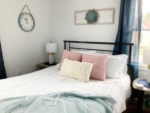 a bed with pink and white pillows and a clock at The Rustic Retreat- close to downtown in Bristol +6 photos