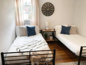 two beds in a living room with a clock on the wall at The Rustic Retreat- close to downtown in Bristol