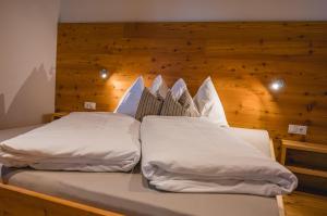 two beds in a room with a wooden wall at Brünnl's Försterhütte in Parcines