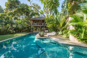 una piscina frente a una casa con árboles en UXUA Alma, en Trancoso