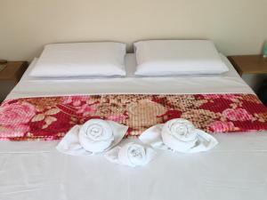 a bed with two white towels and roses on it at RDS Hospedagem in Itacaré