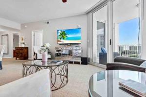 a living room with a couch and a tv at Pink Sunsets at the Palms of Destin Across from Beach, Heated Pool Shuttle & Dining in Destin