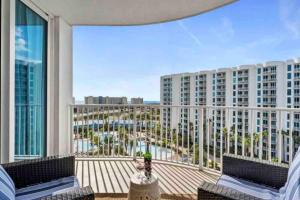 uma varanda com 2 cadeiras e vista para um edifício em Pink Sunsets at the Palms of Destin Across from Beach, Heated Pool Shuttle & Dining em Destin