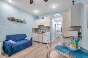 Picturesque Waterfront Studio في كليرووتر بيتش: غرفة معيشة مع أريكة زرقاء ومطبخ