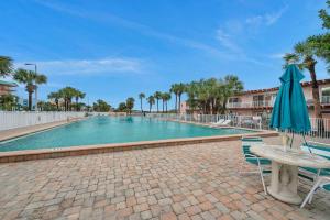 a swimming pool with a table and an umbrella at Picturesque Waterfront Studio in Clearwater Beach