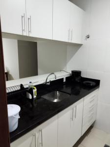 a kitchen with white cabinets and a sink at Excelente Flat no Centro de Manaus próximo ao Teatro Amazonas. in Manaus