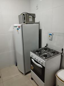 a kitchen with a stove and a microwave on top of a refrigerator at Excelente Flat no Centro de Manaus próximo ao Teatro Amazonas. in Manaus