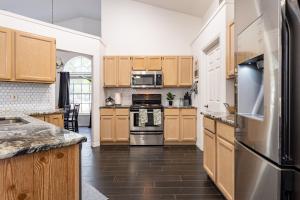 a kitchen with wooden cabinets and stainless steel appliances at East Orlando Getaway - 3BR/2BTH - *Pool *Parking in Orlando