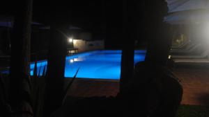 une personne debout en face d'une piscine la nuit dans l'établissement Villa Carlotta Resort, à San Leone