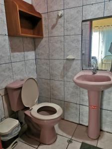 baño con aseo rosa y lavamanos en Mark’s home, en Puerto Ayora