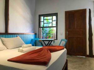 1 dormitorio con cama, ventana y puerta en Chalés Água Grande en Maresias