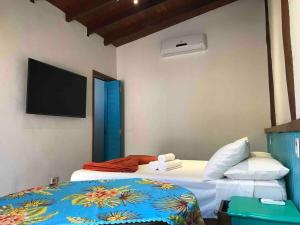 two beds in a room with a tv on the wall at Chalés Água Grande in Maresias