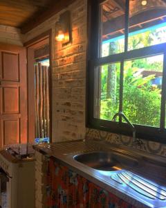 uma cozinha com um lavatório e uma janela em Chalés Água Grande em Maresias