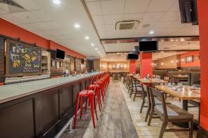 a restaurant with red walls and wooden tables and red stools at Holiday Inn Salina, an IHG Hotel in Salina