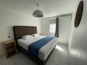 una camera con un letto con una coperta blu e bianca di T3 de Standing aux trois ilets / Vue Mer a Les Trois-Îlets
