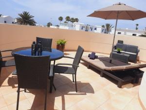 a patio with a table and chairs and an umbrella at Riviera Park Apartamento 2A in Puerto del Carmen