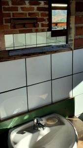 a bathroom with a white sink and a brick wall at Loft no campo próximo ao Vale dos Vinhedos in Garibaldi