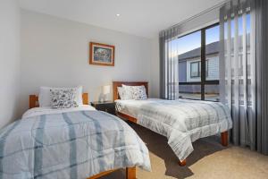 1 dormitorio con 2 camas y ventana en Nexus Townhouse with Parking and Wi-Fi, en Auckland
