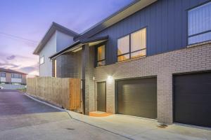 uma casa com duas portas de garagem numa rua em Nexus Townhouse with Parking and Wi-Fi em Auckland