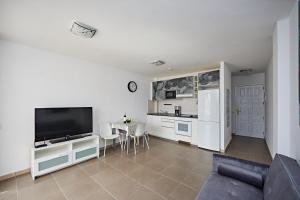 a living room with a large television and a kitchen at Holidays in Paradise in Mogán