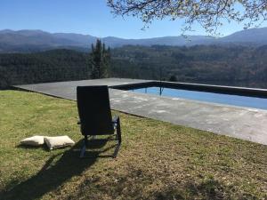 una silla sentada en el césped junto a una piscina en Casa da Eira - Sobrenatura Ecoturismo, en Arcos de Valdevez