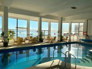 a large swimming pool with chairs and tables in a building at Spectacular Sea Views Torremolinos in Torremolinos