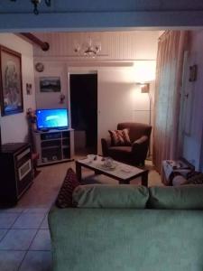 - un salon avec un canapé, une table et une télévision dans l'établissement Το σπίτι της Δήμητρας, à Platamonas