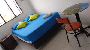 ein blaues Bett mit gelben Kissen, einem Tisch und einem Stuhl in der Unterkunft HOTEL ANAPOIMA PLAZA IN in Anapoima