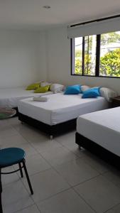 a bedroom with two beds and a chair and a window at HOTEL ANAPOIMA PLAZA IN in Anapoima