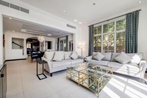 a living room with a white couch and a glass table at Whispering Pines, JGE - Vacationer in Dubai
