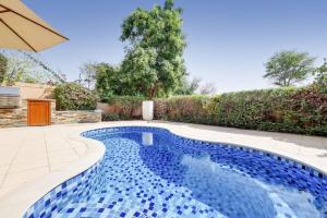 a swimming pool with blue tiles in a backyard at Whispering Pines, JGE - Vacationer in Dubai