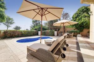 a patio with chairs and an umbrella and a pool at Whispering Pines, JGE - Vacationer in Dubai