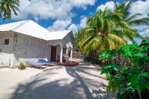 a house on the beach with a palm tree at Baraka house in Kidenga