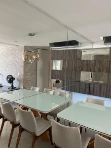 uma sala de jantar com uma mesa de vidro e cadeiras em Apartamento Confortável e Completo - JTR em Maceió