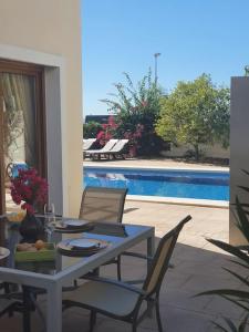 eine Terrasse mit einem Tisch, Stühlen und einem Pool in der Unterkunft Espectacular Villa PISCINA PRIVADA Altaona GOLF in Murcia
