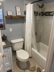 a white bathroom with a toilet and a shower at Minutes to the beach! 4-bedroom home, free parking in Hampton