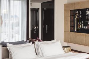 a bedroom with a bed with white pillows and a window at 11 Mirrors Design Hotel in Kyiv