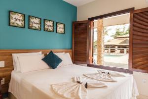 a bedroom with a white bed with a large window at Pousada Algodão da Praia in Araruama