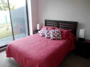 1 dormitorio con 1 cama grande con sábanas y almohadas rojas en Casa Costa Pucón en Pucón