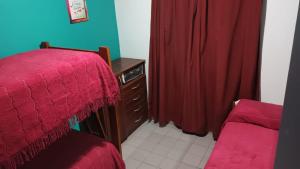 1 dormitorio con 1 cama, vestidor y cortinas rojas en AZUL Y LUNA en Vaqueros