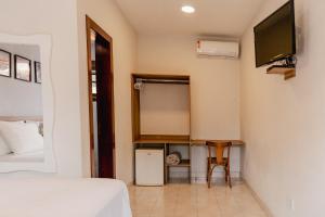 a bedroom with a bed and a tv on the wall at Pousada Algodão da Praia in Araruama
