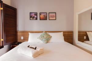 a bedroom with a white bed with two towels on it at Pousada Algodão da Praia in Araruama