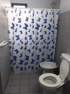 baño con aseo y cortina de ducha con mariposas azules en AZUL Y LUNA en Vaqueros