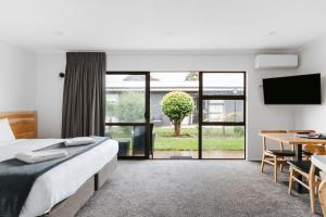 a bedroom with a bed and a table and a television at Cobblestone Court Motel - Wenzel Motels in Tauranga