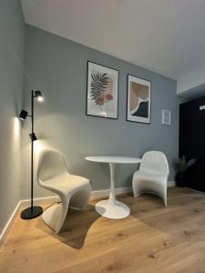 Habitación con mesa y 2 sillas blancas. en Urocze studio przy Rynku, en Wroclaw