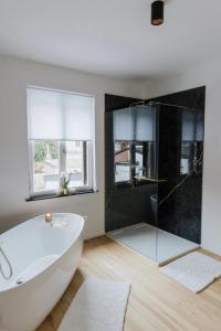 een badkamer met een bad en een glazen douche bij Au Numéro 5 in Tilff