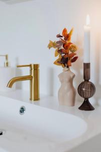 a bathroom sink with a candle and a vase with flowers at Au Numéro 5 in Tilff