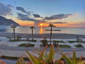 a sunset over a beach with palm trees and the ocean at Appartamento Beatrice in Castellammare di Stabia