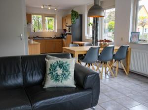 a living room with a black couch and a kitchen at Huisje 11 Wemeldinge in Wemeldinge