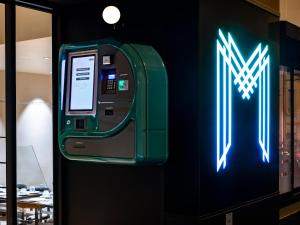 a green atm machine is next to a wall at MOKA Hôtel in Lorient